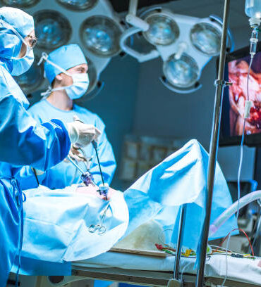 Three surgeons doing laparoscopic surgery. Doctors looking at image on monitor. Medicine and healthcare concept.